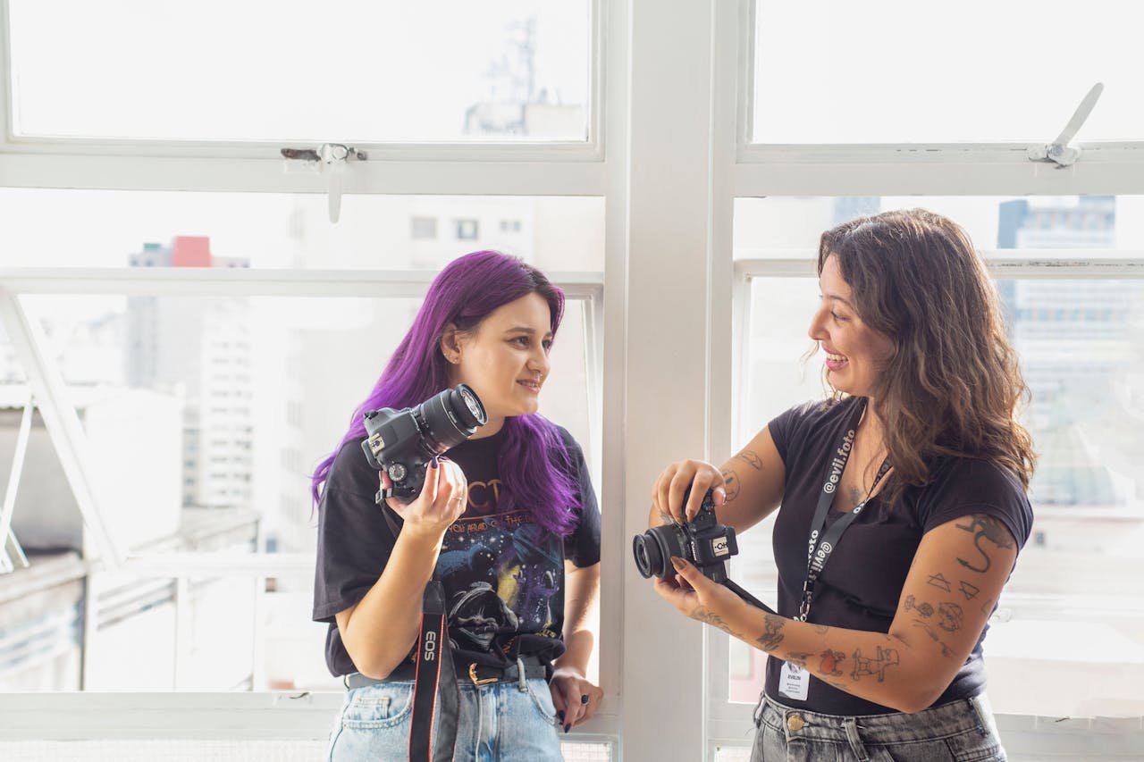 Two women photographers exchanging tips indoors, showcasing a creative workspace.